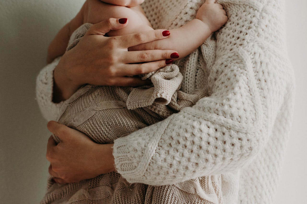 Home Close-up of a mother holding her baby in warm knitwear, conveying love and togetherness.